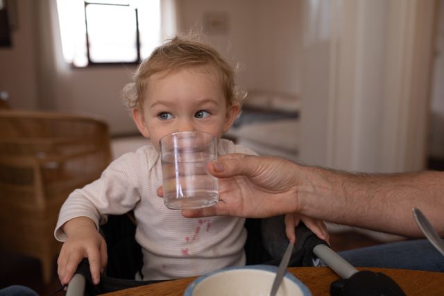 Baby drinking water with his father\\\'s help in the kitchen - Download Free Stock Photos Pikwizard.com