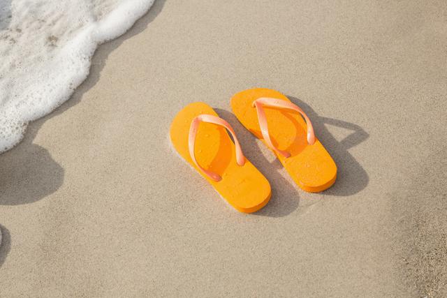 Orange flip flop in sand on beach