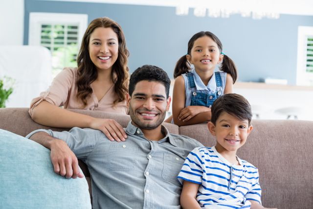 Portrait of happy parents and kids sitting on sofa in living room at home