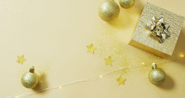 Image of christmas decorations with gold baubles and present on yellow background - Download Free Stock Photos Pikwizard.com